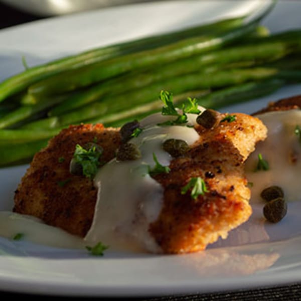 Iavarone's Chicken Piccata with creamy sauce, capers, parsley, and a side of green beans.