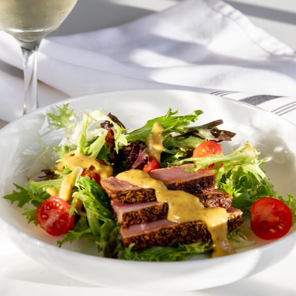 Seared tuna salad with mixed greens, cherry tomatoes, and mustard dressing, with white wine.