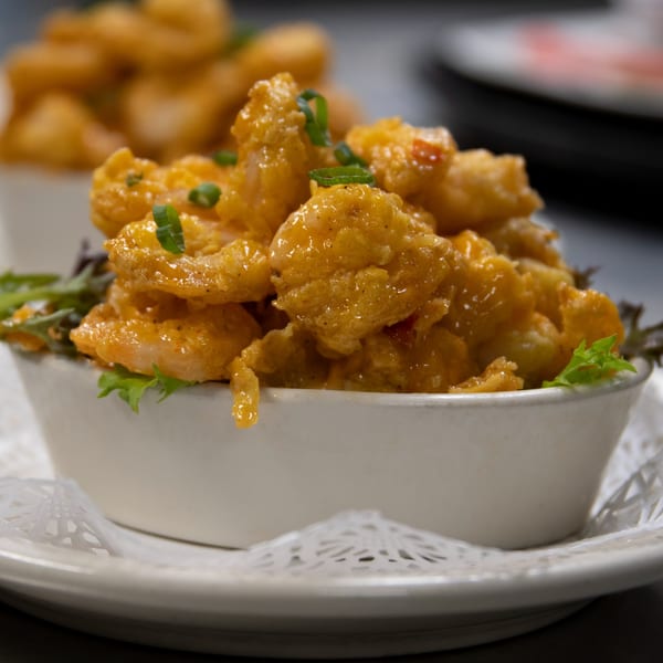 Two white bowls filled with golden-brown fried shrimp, garnished with green onions and lettuce.