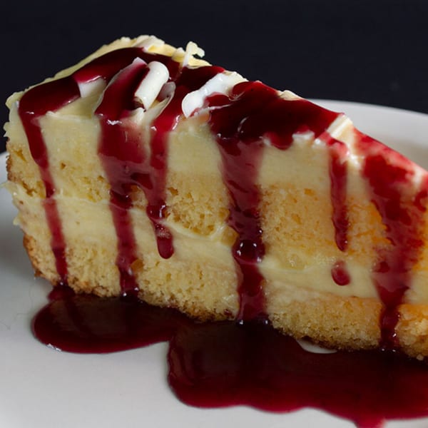 A slice of Iavarone's Italian cheesecake with raspberry sauce and white chocolate shavings.