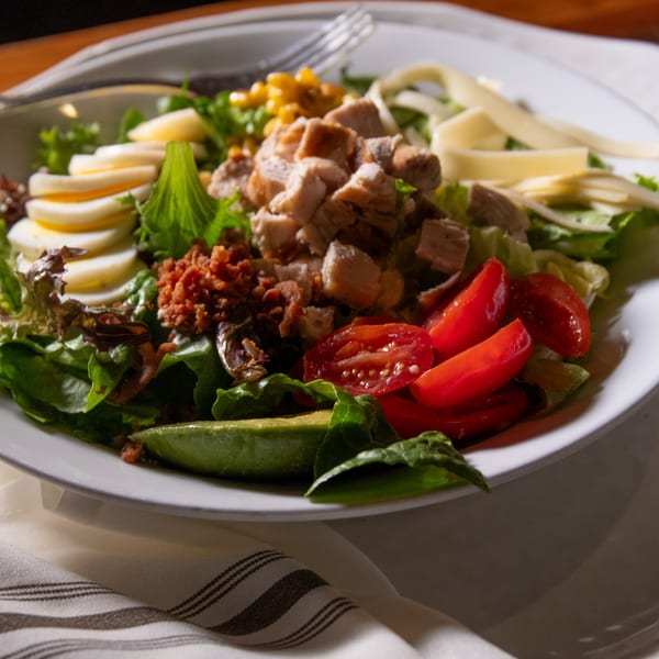 A vibrant Iavarone's Cobb salad with chicken, bacon, eggs, avocado, tomatoes, and cheese.